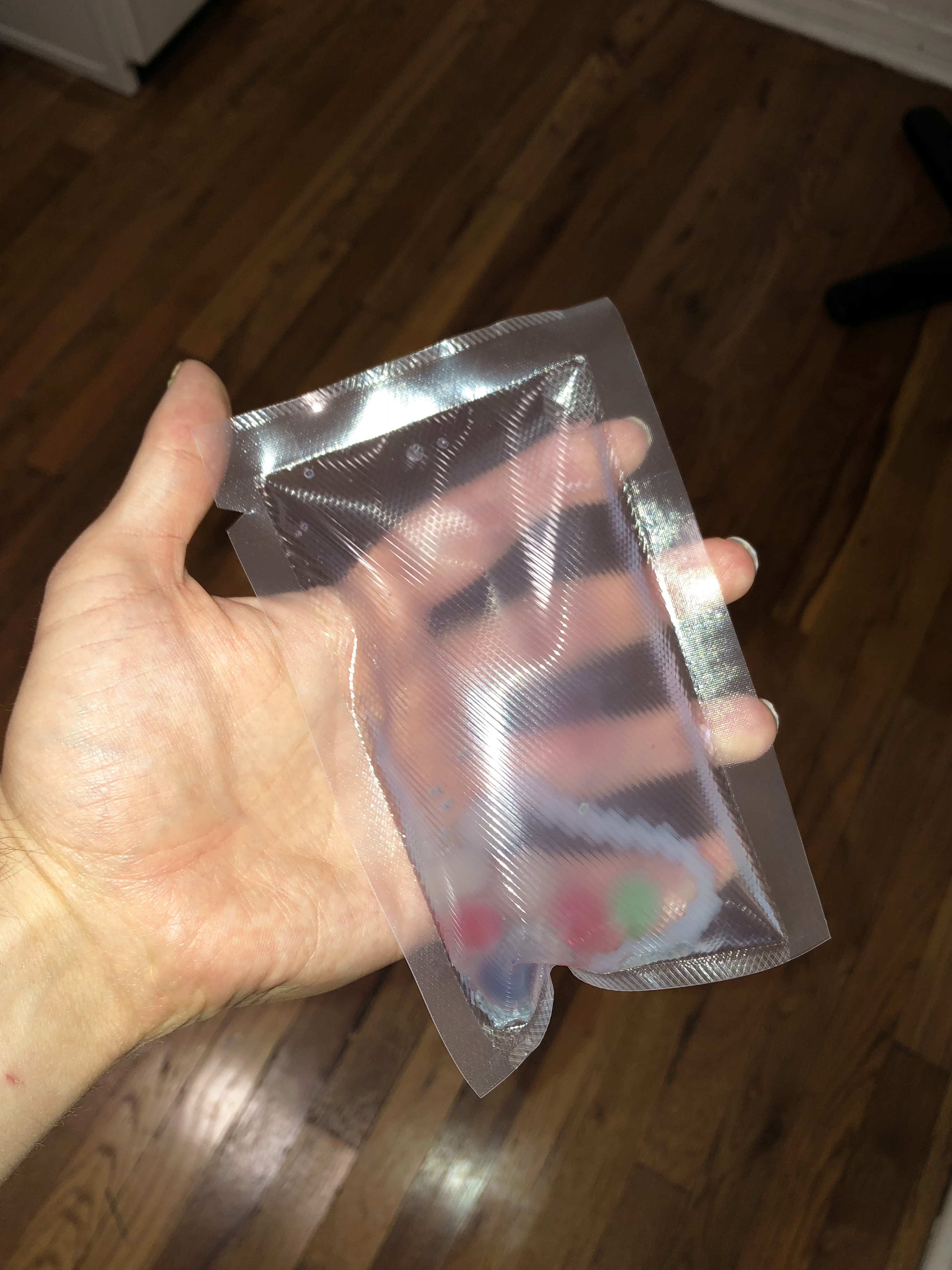 A hand holding a clear pouch full of jelly snacks